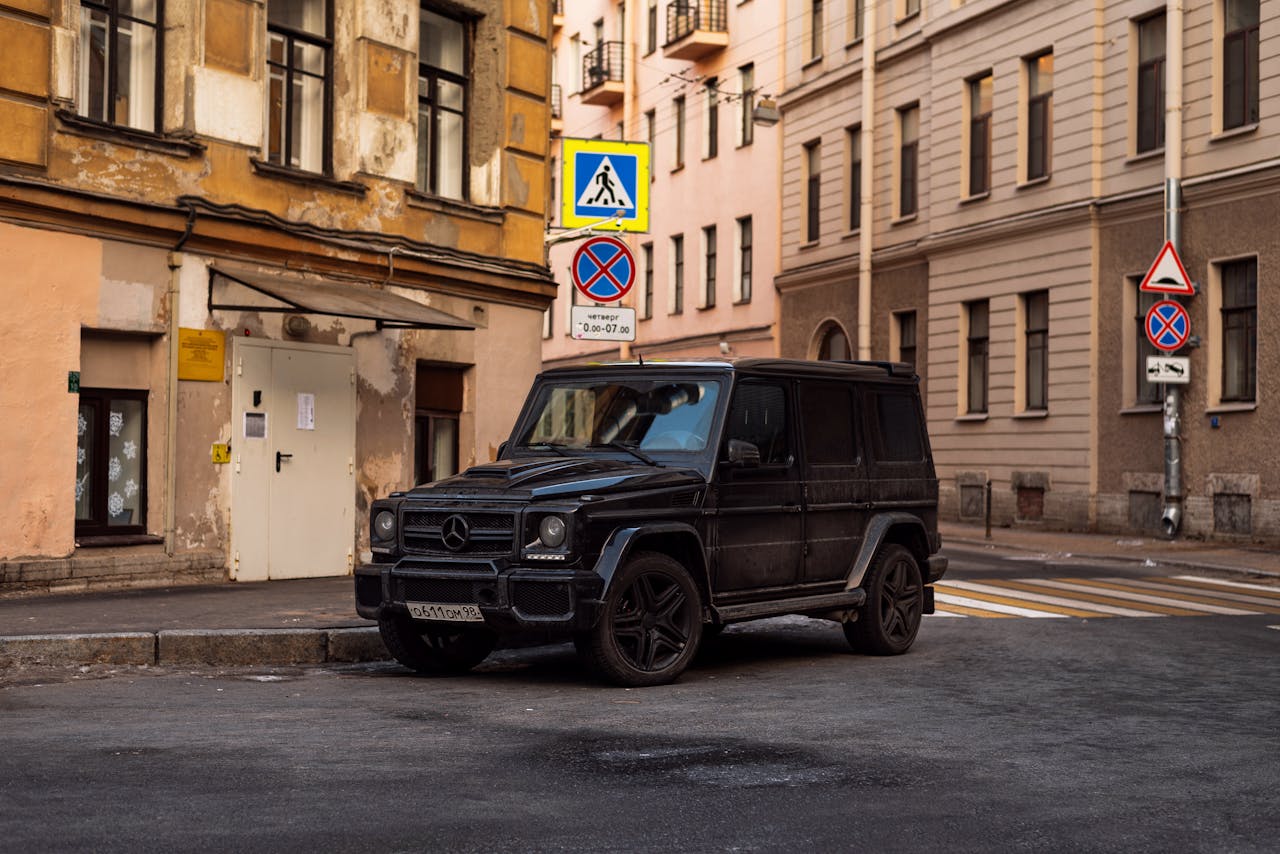 Black SUV parked in urban city street with historic buildings, daylight setting.